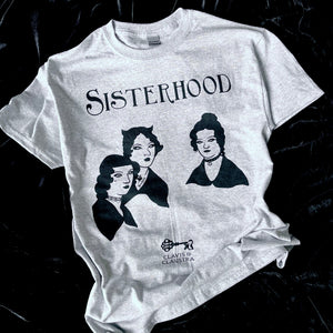 Photo of a grey marl t-shirt with the Bronte sisters iconic portrait except they have had a Goth makeover - they all have black hair, make up and piercings. Above is the caption "Sisterhood". 