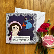 Greetings card featuring quote “I won’t say she was silly but I think one of us was silly and it wasn’t me“ from Elizabeth Gaskell‘s wives and daughters, accompanied by cartoon illustration of a woman raising her eyebrow in the foreground while another woman dances with a traffic cone and a bottle of champagne in the background. Card sits on wooden table with flowers.