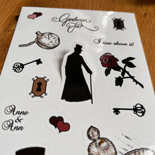 Load image into Gallery viewer, Close-up photo of a glossy A6 sheet with Gentleman Jack stickers: interlocking pink and black hearts; “Gentleman Jack” in stylised writing; a dark keyhole; a rose with thorns; a pocket watch and chain; an ornate iron key; a light keyhole; a silhouette of Anne Lister with a top hat and cane; an ornate iron key with a different design, interlocking burgundy and black hearts; “I rise above it!” In stylised writing; “Anne &amp; Ann” in stylised writing; a top hat; and a quill and ink pot.