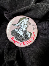 Load image into Gallery viewer, Photo of a pocket mirror, with a brown background and black-and-white mediaeval woodcut artwork of stereotypical crone with warts and a large nose. The caption reads 'Resting Witch Face' in a red Gothic typeface. Positioned on black fabric.