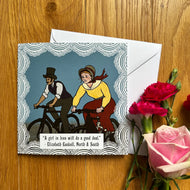 Greetings card featuring the quote “ A girl in love will do a great deal“ from Elizabeth Gaskell’s north and south, with accompanying cartoon illustration of a couple in Victorian clothing riding bicycles, with the woman visibly sweaty and uncomfortable following the man. The card sits next to flowers on a table.