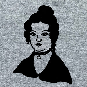 Close up of Charlotte Bronte who is wearing a black studded collar with a ring at the front. She has a nose ring and a lip piercing and dramatic eye make up.