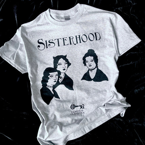 Photo of a grey marl t-shirt with the Bronte sisters iconic portrait except they have had a Goth makeover - they all have black hair, make up and piercings. Above is the caption 