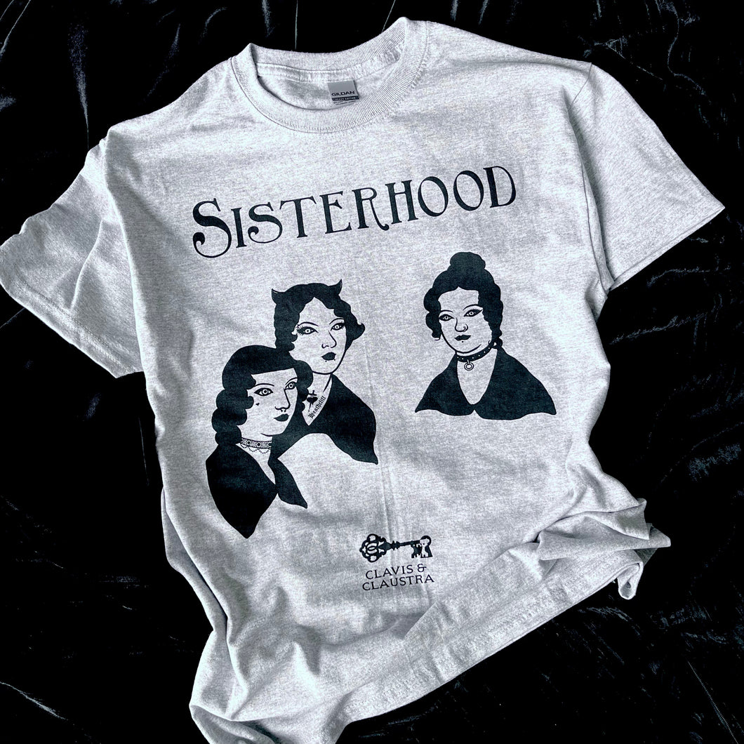 Photo of a grey marl t-shirt with the Bronte sisters iconic portrait except they have had a Goth makeover - they all have black hair, make up and piercings. Above is the caption 