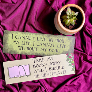 Photo of 2 bookmarks laid out next to a tiny plant. The green bookmarks sit on a purple fabric and feature quotes from Wuthering Heights, with images of a book and ivy.
