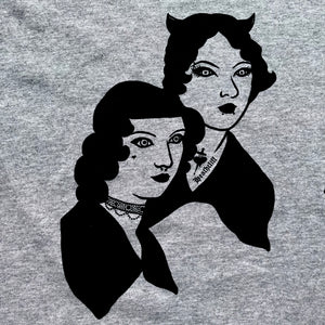 Close up of Emily and Anne Bronte. Anne has a tiny heart tattoo on her cheek, and a septum piercing, along with a beaded choker. Emily has a Heathcliff tattoo, lip piercings, an eyebrow piercing, and horns! 