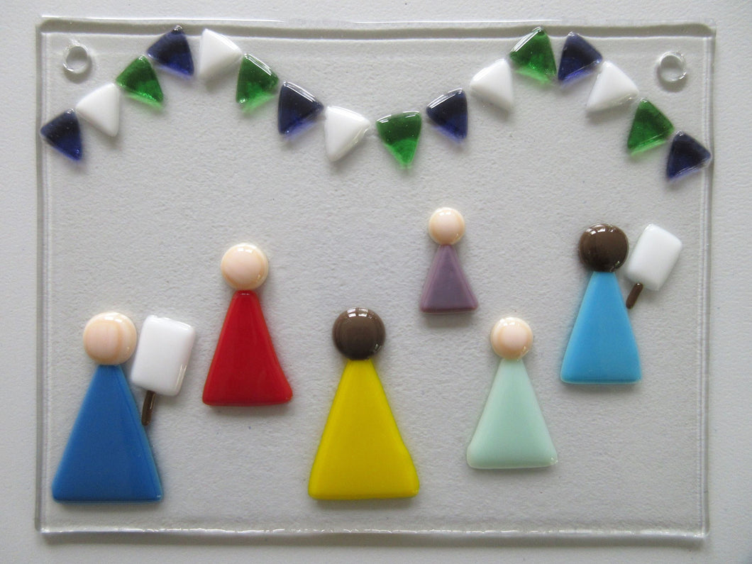 Photo of the glass artwork, which features six women in a minimalist style holding placards and underneath some bunting in suffragette colours. The glass artwork features two holes at the top corners for mounting.