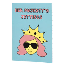 Load image into Gallery viewer, Photo of Her Majesty’s Jottings notebook with the title in pink, featuring a blue cover with a stylised illustration of an unsmiling woman with long pink hair, wearing sunglasses and an extravagant yellow crown.