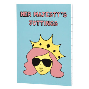 Photo of Her Majesty’s Jottings notebook with the title in pink, featuring a blue cover with a stylised illustration of an unsmiling woman with long pink hair, wearing sunglasses and an extravagant yellow crown.