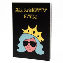Load image into Gallery viewer, Photo of Her Majesty’s Notes notebook with the title in yellow-outlined letters, featuring a black cover with a stylised illustration of an unsmiling woman with long blue hair, wearing sunglasses and an extravagant yellow crown.