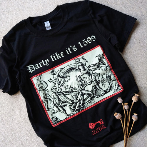Photo of a black t-shirt featuring a black-and-white mediaeval woodcut artwork on a black background and framed in red, depicting several demons cavorting around a gigantic ring. One plays some bagpipes, another the lute. Above it the caption reads 'Party like it’s 1599' in a white Gothic typeface. Underneath is the Clavis & Claustra logo in red. A plant lies next to the shirt.