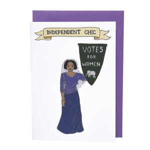 Photo of a greetings card depicting a suffragette in a headscarf and a purple top and skirt, holding a pennant that reads “Votes For Women” with an elephant at the base. Above is a banner reading "Independent Chick" and the background is white. Behind the card is a purple envelope.