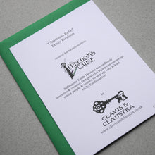 Load image into Gallery viewer, Photo of the back of the card on top of a green envelope, showing the Clavis &amp; Claustra key logo, To Freedom’s Cause Emily Davison logo, and text that reads “‘Christmas Rebel’” and “Emily Davison” and “created for #Emilymatters” and “Suffragette Emily Davison was endlessly inventive and creative. Her powerful legacy can encourage young people &amp; women to step up, vote &amp; lead.” And “bit.ly/Emilymatters”