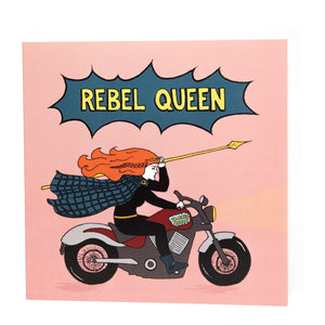 Photo of a pink card featuring Boudicca, with her ginger hair in a whirl around her as she raises a yellow spear and rides a motorcycle. Above her, a dark blue exploding bubble with “Rebel Queen” in yellow text.