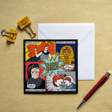 Load image into Gallery viewer, Photo of the card on a white envelope. The image is divided in four, showing a woman with giant red hair and holding a spear (“Boudicca, slayin’”); a pharaoh (“Hatshepsut, stone-cold boss”) scowling as someone out of shot shouts “Nice lady-beard!”; Queen Victoria with a thought bubble that says “We are not amused!” (“Queen Vic, throwing shade”); and Mary, Queen of Scots and Queen Elizabeth I scowling and butting heads (“QE1 vs MQS, Dames of Thrones”). Next to the card is a document clip and red pen.