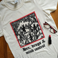 Photo of a white t-shirt featuring a mediaeval woodcut artwork depicting witches and demons joining hands and dancing in a circle, framed by a thin red border. Beneath it the caption reads 'Hex, drugs & mind control'. A closed pair of glasses and a red lipstick are on top of the fabric.