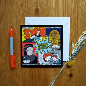 Photo of the card on a white envelope. The image is divided in four, showing a woman with giant red hair and holding a spear (“Boudicca, slayin’”); a pharaoh (“Hatshepsut, stone-cold boss”) scowling as someone out of shot shouts “Nice lady-beard!”; Queen Victoria with a thought bubble that says “We are not amused!” (“Queen Vic, throwing shade”); and Mary, Queen of Scots and Queen Elizabeth I scowling and butting heads (“QE1 vs MQS, Dames of Thrones”). Next to the card is a sprig of wheat and marker pen.