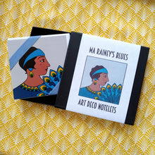 Load image into Gallery viewer, Photo of the notelets bound by a white sleeve, captioned: “Ma Rainey’s Blues Art Deco Notelets.” At the centre is an Art Deco-style illustration of Ma Rainey, a Black woman in a blue dress and headband holding a blue and yellow feather fan. The box is open to show the same illustration in a larger style, with a blue ribbon around one corner.