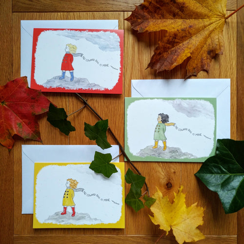 Three variants of the card, all with the same artwork in different colours: a girl in boots and a coat standing on the moors, as the wind blows through her hair. Behind her is the caption “No coward soul is mine - Emily Bronte.” There are variants in red and green and yellow. Next to the cards are some autumn leaves.