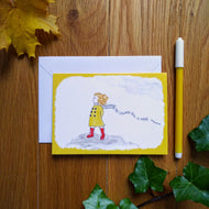 The card in yellow: a girl in red boots and a yellow coat and blue scarf standing on the moors, as the wind blows through her ginger hair. Behind her is the caption “No coward soul is mine - Emily Bronte”. Next to the cards are some autumn leaves and a felt tip pen.