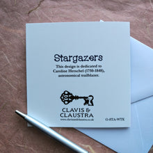 Load image into Gallery viewer, Photo of the back of the card. Shows the Clavis &amp; Claustra key logo and text that says “Stargazers” and “This design is dedicated to Caroline Herschel (1750-1848), astronomical trailblazer.”