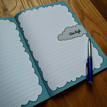 Load image into Gallery viewer, Photo of the open notebook, showing two blank lined pages with fringes of light blue to resemble clouds. A grey cloud is on the right page with “Go high” inside. A pen has been placed next to the notebook.