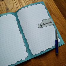 Load image into Gallery viewer, Photo of the open notebook, showing blank lined pages with light blue fringes to make the pages resemble clouds and “Go the extra mile” written in a gray cloud. A pen is resting on the page.