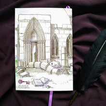 Load image into Gallery viewer, Photo of the back of the Thornfield Hall notebook, depicting a crumbling Gothic ruin with a purple ribbon emerging from the pages, with walls and columns  and windows broken into rocks on the grass. The head of a statue likes on the ground. In the bottom-left corner is the Clavis &amp; Claustra purple key logo. Next to the book is a black quill.
