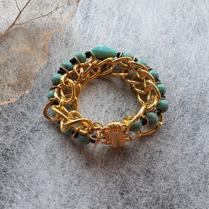 Photo of the bracelet, consisting of golden links that interweave with turquouise beads. The bracelet is clasped in a circle.