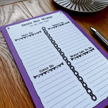 Load image into Gallery viewer, A photo of a notepad at an oblique angle with a pen and a cup of black tea. The pad has a purple border and is entitled &#39;Deeds Not Words&#39; with the page sectioned off into &#39;Must do&#39;, &#39;Should do&#39;, &#39;Could do&#39; and &#39;Would like to do&#39;, decorated with chains and bunting.